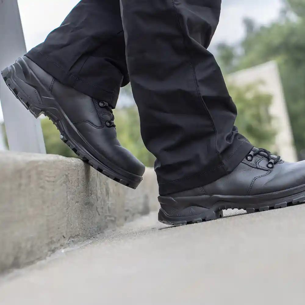 Black Enforce X High Winter work boots worn with black pants stepping off a concrete ledge, featuring shock absorption.