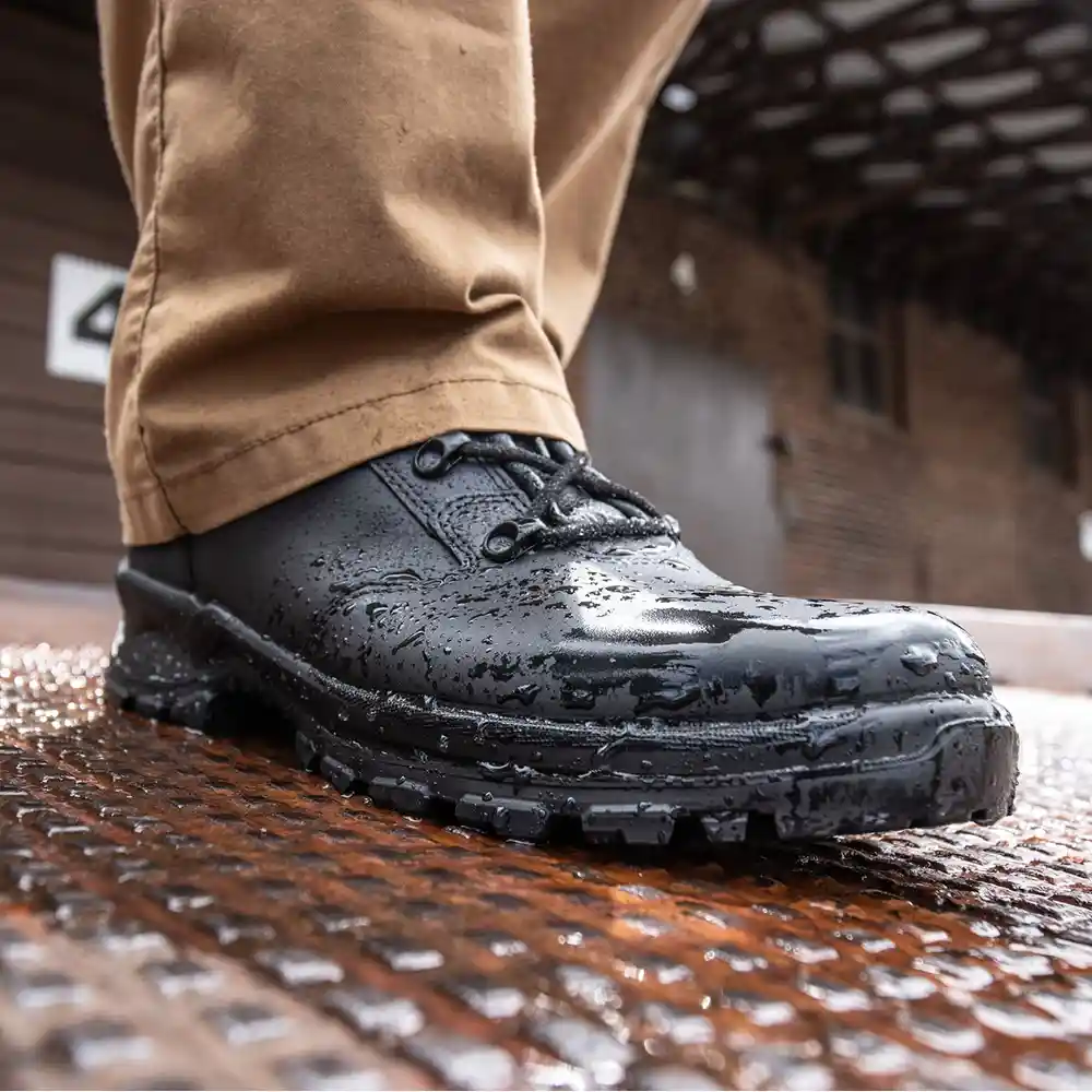 Close-up on black Enforce X High Winter tactical boots covered in water over a wet surface, featuring a waterproof lining.