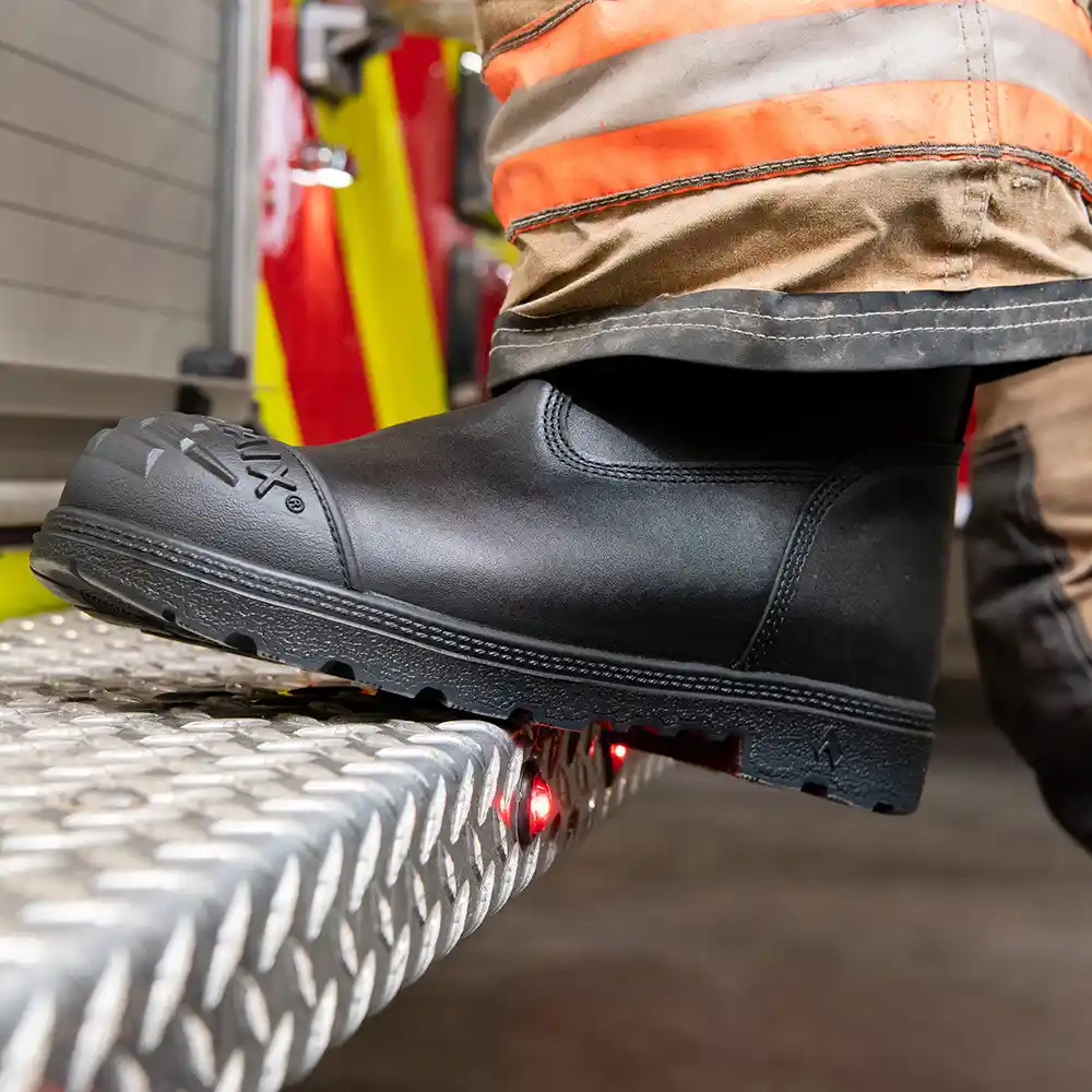 Black Fire Hunter USA fire boots worn with turnout gear perched on metal diamond plate surface featuring anti-slip support